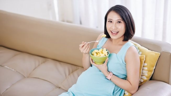 Illustration of pregnant woman eating pineapple.  (Envato Elements)