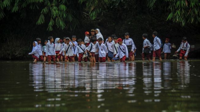 Sejumlah siswa menyeberangi Sungai Ciujung untuk sekolah di Desa Sukaluyu, Cikadu, Cianjur Selatan, Kabupaten Cianjur, Jawa Barat, Rabu (10/8/2022).  ANTARA FOTO/Raisan Al Farisi