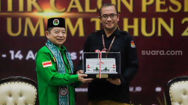 Ketua Komisi Pemilihan Umum (KPU) Hasyim Asy'ari (kanan) memberikan cinderamata kepada Ketua Umum Partai Persatuan Pembangunan (PPP)  Suharso Monoarfa saat Pendaftaran Partai Politik Calon Peserta Pemilu tahun 2024 di Kantor KPU, Jakarta Pusat, Rabu (10/8/2022). [Suara.com/Alfian Winanto]