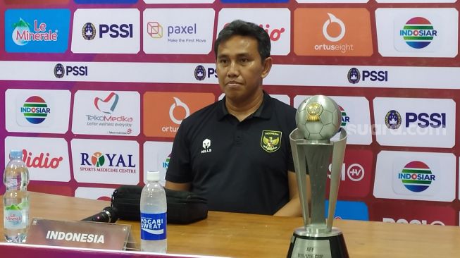 Pelatih timnas Indonesia U-16, Bima Sakti dan trofi Piala AFF U-16 2022. (Suara.com/Arif Budi)