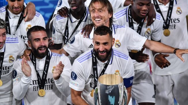 Penyerang Real Madrid, Karim Benzema (tengah) memegang trofi Piala Super Eropa setelah mengalahkan Eintracht Frankfurt di Finlandia, Kamis (11/8/2022) dini hari WIB. [OLGA MALTSEVA / AFP]