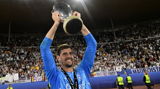 Kiper Real Madrid, Thibaut Courtois mengangkat trofi Piala Super Eropa usai mengalahkan Eintracht Frankfurt 2-0 di Helsinki, Finlandia, Kamis (11/8/2022) WIB. [JAVIER SORIANO / AFP]