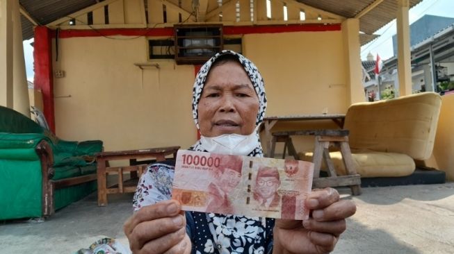 Nurhayati, pedagang kelling, menunjukkan uang palsu yang diterimanya dari seorang pembeli. [Lampungpro.co]