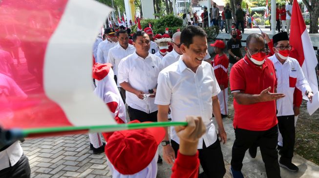 Wakil Menteri Dalam Negeri (Wamendagri) John Wempi Wetipo (kedua kanan) didampingi Penjabat Gubernur Aceh Achmad Marzuki (ketiga kanan) dan Penjabat Wali Kota Banda Aceh Bakri Siddiq (kanan) disambut para pelajar saat peluncuran dan penyerahan bendera pada Gerakan 10 juta Bendera Merah Putih di Banda Aceh, Aceh, Sabtu (13/8/2022). [ANTARA FOTO/Irwansyah Putra/nym]