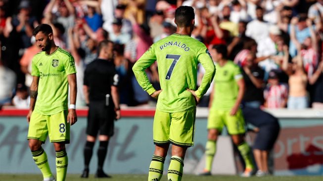 Gelandang Manchester United Bruno Fernandes (kiri) dan penyerang Manchester United Cristiano Ronaldo (tengah) bereaksi setelah tertinggal dua gol saat pertandingan sepak bola Liga Premier Inggris antara Brentford dan Manchester United di Stadion Brentford Community, London, Inggris, Sabtu (13/8/2022). [Ian Kington / AFP]