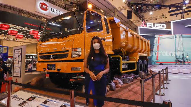 Sales Promotion Girl (SPG) berpose di depan Truk Fuso yang dipamerkan pada ajang pameran otomotif Gaikindo Indonesia International Auto Show (GIIAS) 2022 di Indonesia Convention Exhibition (ICE) BSD, Serpong, Tangerang, Banten, Sabtu (13/8/2022). [Suara.com/Alfian Winanto]