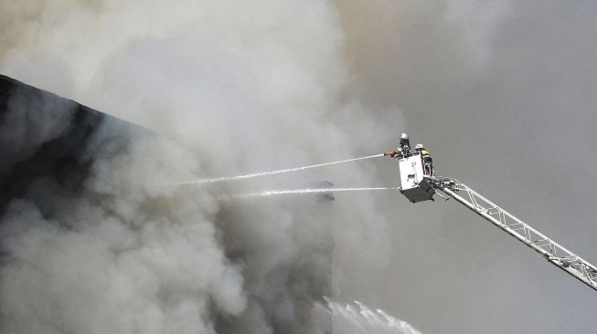 Petugas pemadam berusaha memadamkan gudang kembang api yang terbakar di Pasar Surmalu, Yerevan, Armenia, Minggu (14/8/2022). [Karen MINASYAN / AFP]