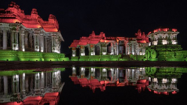 Kuil batu dan monumen Hampi terlihat menyala dengan warna bendera India di Hampi, India, Senin (8/8/2022). [Shivashankar BANAGAR / AFP]