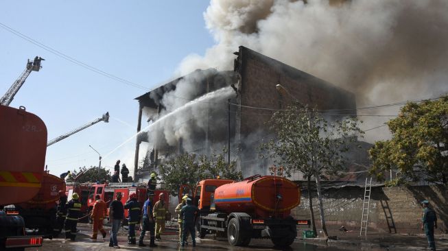 Petugas pemadam berusaha memadamkan gudang kembang api yang terbakar di Pasar Surmalu, Yerevan, Armenia, Minggu (14/8/2022). [Karen MINASYAN / AFP]