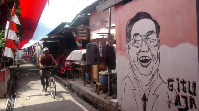 Warga melintas di bawah bendera merah putih terpanjang di Desa Pekauman Kulon, Kabupaten Tegal, Jawa Tengah, Senin (15/8/2022). [ANTARA FOTO/Oky Lukmansyah/foc]
