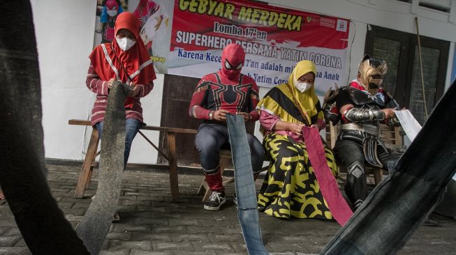 Relawan mengenakan kostum superhero bersama warga mengikuti lomba melipat stagen di Sukoharjo, Jawa Tengah, Selasa (16/8/2022).  ANTARA FOTO/Mohammad Ayudha