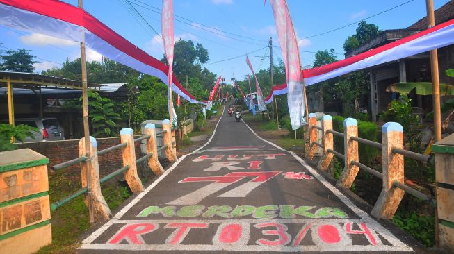 Warga melintas disamping bendera merah putih terpanjang di Desa Honggosoco, Jekulo, Kudus, Jawa Tengah, Selasa (16/8/2022). ANTARA FOTO/Yusuf Nugroho
