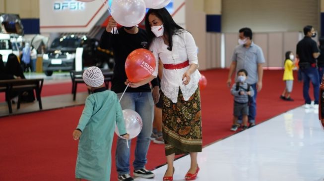 Seorang usher (atribut merah putih) tengah membagikan balon merah putih dari booth Isuzu [GIIAS/Seven Events].