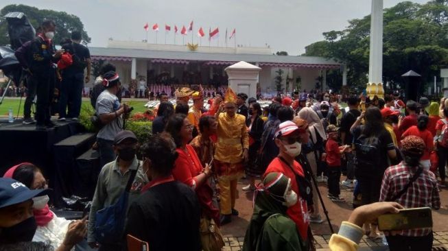 Suasana kerumunan warga berfoto di depan Istana Negara jelang Upacara Penurunan Bendera Merah Putih yang digelar pada Rabu (17/8/2022) sore. [Suara.com/Rakha Ariyanto]