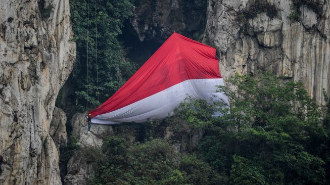 Atlet panjat tebing FPTI, anggota Mahapeka serta berbagai komunitas panjat tebing mengibarkan bendera raksasa saat upacara kemerdekaan di Geotheater Tebing Hawu, Padalarang, Kabupaten Bandung Barat, Jawa Barat, Rabu (17/8/2022).  ANTARA FOTO/Raisan Al Farisi