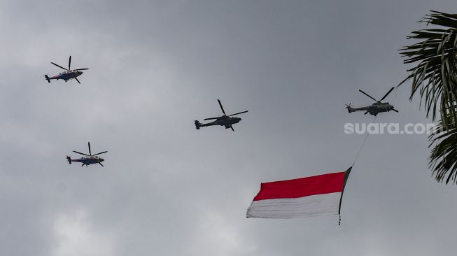 Helikopter gabungan milik TNI-Polri terbang melintas dengan bendera merah putih raksasa di atas Monas saat Peringatan Detik-Detik Proklamasi di Perpustakaan Nasional, Jakarta Pusat, Rabu (17/8/2022). [Suara.com/Alfian Winanto]