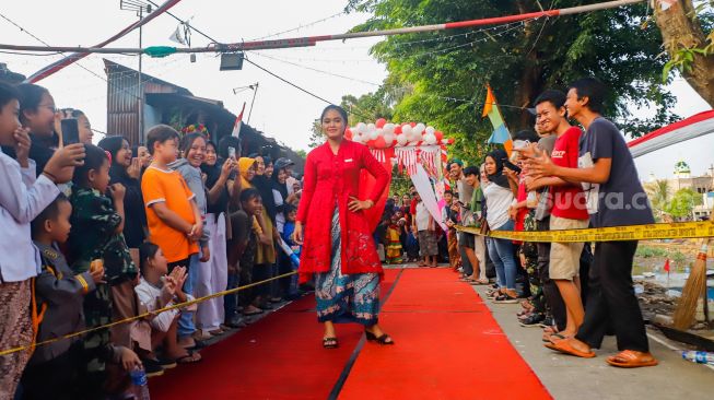 Peserta berpose saat mengikuti acara 'Ciliwung Fashion Week' di Kebon Baru, Jakarta Selatan, Rabu (17/8/2022). [Suara.com/Alfian Winanto]