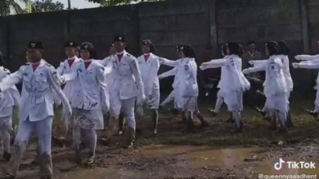 Tangkapan layar video viral paskibra Panimbang, Kabupaten Pandeglang, Banten melintasi jalan rusak dan kubangan demi mengibarkan bendera merah putih, Rabu (17/8/2022). [TikTok]