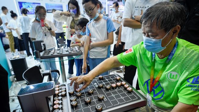 Pengunjung bermain catur Cina dengan robot pada acara Konferensi Robot Dunia 2022 di Beijing, China, Kamis (18/8/2022). [WANG Zhao/AFP]