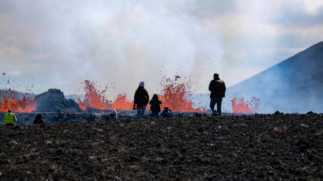 Sejumlah orang mengunjungi lokasi erupsi Gunung Fagradalsfjall di Grindavik, Islandia, Kamis (4/8/2022). [Jeremie RICHARD / AFP]