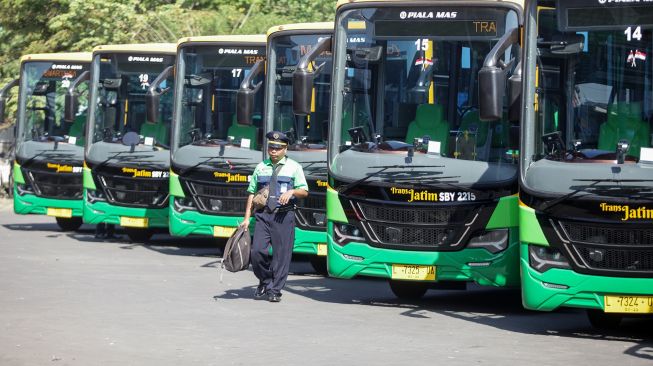 Pengemudi melintas di depan armada bus TransJatim koridor Sidoarjo-Surabaya-Gresik saat peluncuran perdana bus di Terminal Porong, Sidoarjo, Jawa Timur, Jumat (19/8/2022). ANTARA FOTO/Umarul Faruq

