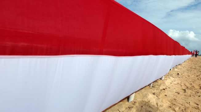 Peserta gowes merah putih mengangkat sepeda untuk melewati bendera merah putih di pantai wisata pulau Kapuk, Lhoknga, Aceh Besar, Aceh, Sabtu (20/8/2022).  ANTARA FOTO/Irwansyah Putra

