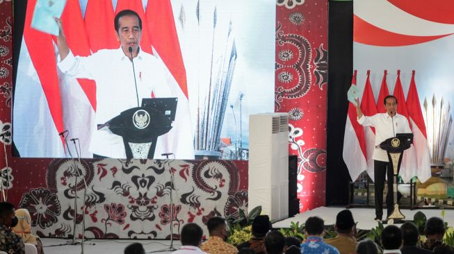 Presiden Joko Widodo mengangkat sertifikat tanah warga saat penyerahan sertipikat tanah untuk rakyat Jawa Timur di Gelora Delta Sidoarjo, Jawa Timur, Senin (22/8/2022).. ANTARA FOTO/Umarul Faruq
