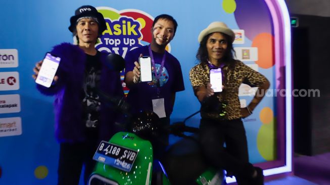 Chief Operating Officer Ovo Eddie Martono (tengah) bersama personil grup band Slank Bimbim (kiri) dan Kaka (kanan) menunjukkan tampilan layar aplikasi usai melakukan pengisian dana saat acara 'Asik Top Up Ovo di Mana Saja' di M Bloc Space, Jakarta Selatan, Selasa (23/8/2022). [Suara.com/Alfian Winanto]