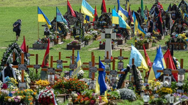 SSeorang wanita berjalan melewati pemakaman selama upacara untuk tentara Ukraina yang gugur di Pemakaman Lychakiv, Lviv, Ukraina, Rabu (24/8/2022). [YURIY DYACHYSHYN / AFP]