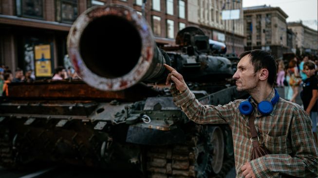 Seorang pria melihat tank Rusia yang hancur di jalan Khreshchatyk, Kyiv, Ukraina, Minggu (21/8/2022). [Dimitar DILKOFF / AFP]