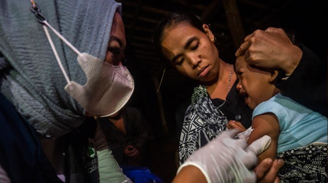 Bidan Puskesmas Cisimeut menyuntikkan vaksin campak kepada seorang anak Suku Baduy di Kampung Cisadane, Lebak, Banten, Jumat (26/8/2022) malam. [ANTARA FOTO/Muhammad Bagus Khoirunas/wsj]