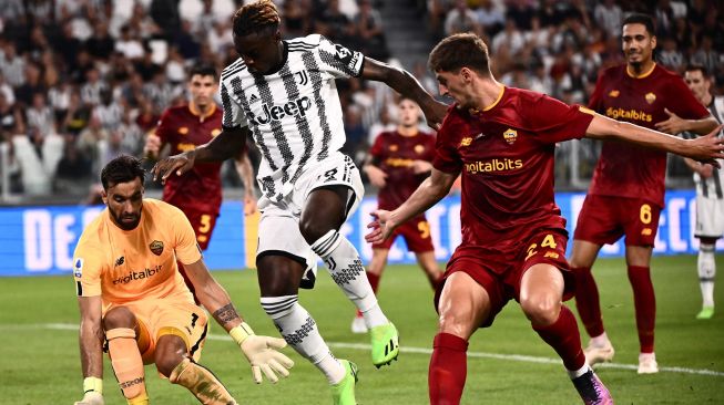 Penyerang Juventus Moise Kean (kedua kiri) menantang kiper AS Roma Rui Patricio (kiri) meskipun bek AS Roma dari Albania Marash Kumbulla (kanan) selama pertandingan sepak bola Serie A Italia antara Juventus melawan AS Roma  di Stadion Allianz, Minggu (28/8/2022) dini hari WIB.Marco BERTORELLO / AFP