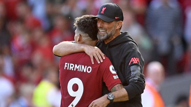 Manajer Liverpool Jurgen Klopp (kanan) memeluk striker Liverpool asal Roberto Firmino (kiri) saat ia digantikan selama pertandingan sepak bola Liga Premier Inggris antara Liverpool melawan Bournemouth di Anfield, Sabtu (27/8/2022) malam WIB, Oli SCARFF / AFP
