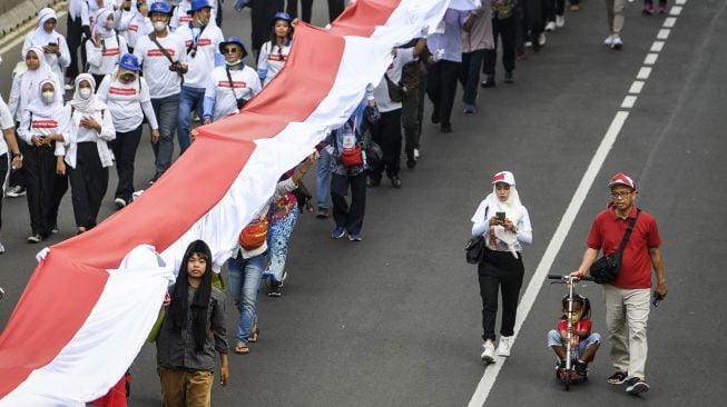 Peserta membentangkan Bendera Merah Putih di kawasan Thamrin, Jakarta, Minggu (28/8/2022). ANTARA FOTO/M Risyal Hidayat