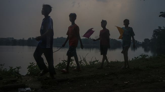 Siluet sejumlah anak dengan latar belakang awan mendung di kawasan Situ Cikaret, Cibinong, Kabupaten Bogor, Jawa Barat, Senin (29/8/2022).  ANTARA FOTO/Yulius Satria Wijaya