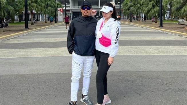 Jennifer Dunn dan Faisal Harris berpose dengan latar belakang Stadion Utama Gelora Bung Karno, Senayan, Jakarta. Namun Jennifer yang melepas hijab menjadi perhatian warganet. [Instagram]