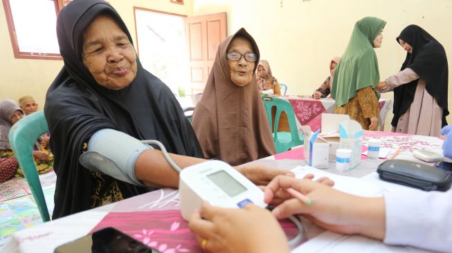 Petugas kesehatan memeriksa tekanan darah dari seorang warga lanjut usia (lansia) di Posyandu Ayeum Mata, Desa Alue Raya, Samatiga, Aceh Barat, Aceh, Rabu (31/8/2022). [ANTARA FOTO/Syifa Yulinnas/wsj]