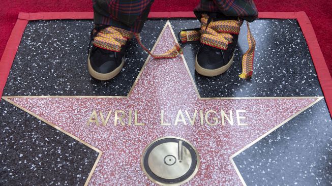 Penyanyi Avril Lavigne menginjak bintang barunya di Hollywood o Fame setelah upacara penghargaan untuknya, di Los Angeles, Rabu (31/8).  VALERIE MACON / AFP

