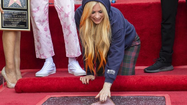 Penyanyi Avril Lavigne berpose di atas bintang barunya di Hollywood o Fame setelah upacara penghargaan untuknya, di Los Angeles, Rabu (31/8).  VALERIE MACON / AFP

