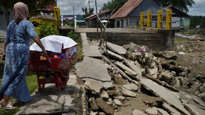 Warga berusaha melewati jalan yang putus akibat abrasi sungai di Desa Muarasampara, Konawe, Sulawesi Tenggara, Kamis (1/9/2022). ANTARA FOTO/Jojon