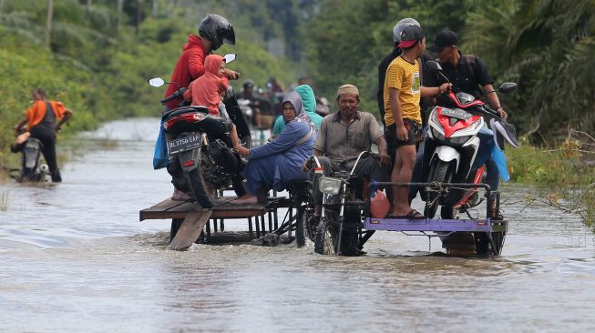 Pengendara memanfaatkan jasa angkut kendaraan roda dua untuk melintasi jalan yang terendam banjir di Desa Layung, Bubon, Aceh Barat, Aceh, Jumat (2/9/2022).  ANTARA FOTO/Syifa Yulinnas
