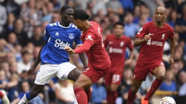 Bek Liverpool Virgil van Dijk mencoba menghentikan pergerakan pemain Everton dalam pertandingan Liga Inggris di Goodison Park, Sabtu (3/9/2022). [AFP]