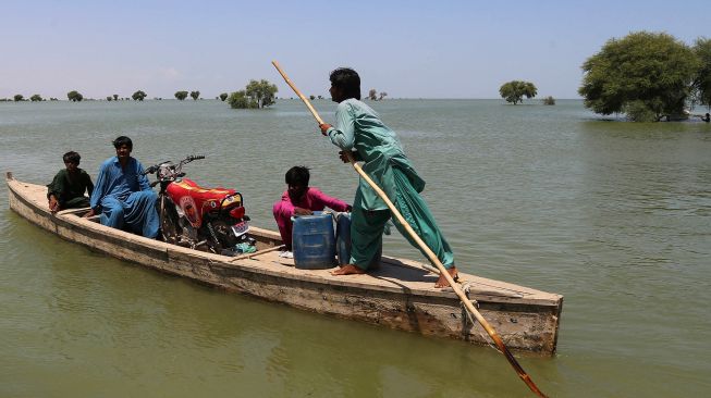 Para pengungsi menyebrangi daerah banjir dengan menggunakan perahu untuk evakuasi di Sehwan di provinsi Sindh, Pakistan, Rabu (31/8/2022). [Akram SHAHID / AFP]
