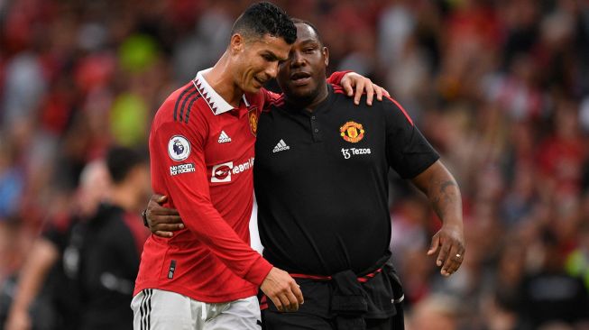 Striker Manchester United Cristiano Ronaldo (kiri) dengan pelatih tim Benni McCarthy (kanan) jalan bersama usai pertandingan sepak bola Liga Premier Inggris antara Manchester United dan Arsenal di Stadion Old Trafford, Manchester, Inggris, Minggu (4/9/2022). [Oli SCARFF / AFP]
