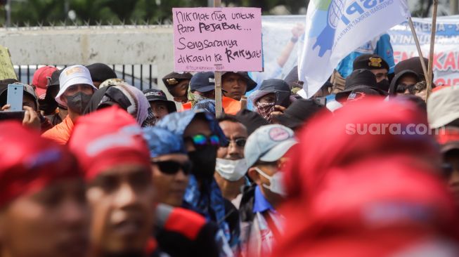 Massa Buruh membawa sejumlah tulisan saat menggelar aksi unjuk rasa di depan Gedung DPR RI, Senayan, Jakarta Pusat, Selasa (6/9/2022). [Suara.com/Alfian Winanto]