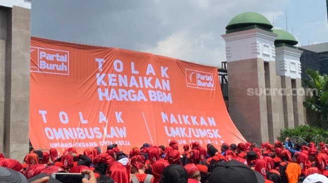 Partai Buruh beserta serikat buruh menggelar aksi penolakan kenaikan harga BBM di depan Gedung DPR RI, Jakarta Pusat, Selasa (6/9/2022) hari ini. Di lokasi, massa memasang spanduk rasksasa sebagai simbol unjuk rasa tersebut. (Suara.com/Rakha)