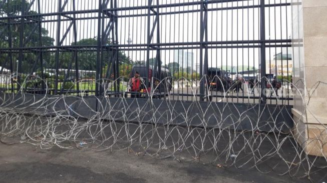 Pintu pagar gedung DPR dikelilingi kawat berduri jelang demo besar-besaran buruh tolak kenaikan BBM. (Suara.com/Rakha)