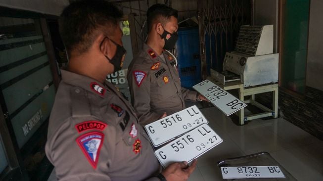 Polisi Lalu Lintas mengecek pelat nomor warna putih yang telah dicetak di Kantor Samsat Kabupaten Batang, Jawa Tengah, Selasa (6/9/2022). ANTARA FOTO/Harviyan Perdana Putra/wsj.