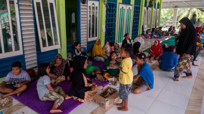 Sejumlah warga korban banjir menyantap bantuan nasi bungkus di teras Masjid Al-Anshar di Desa Pakuli Utara, Gumbasa, Sigi, Sulawesi Tengah, Selasa (6/9/2022). [ANTARA FOTO/Basri Marzuki/tom]
