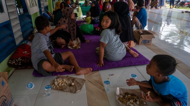 Sejumlah warga korban banjir menyantap bantuan nasi bungkus di teras Masjid Al-Anshar di Desa Pakuli Utara, Gumbasa, Sigi, Sulawesi Tengah, Selasa (6/9/2022). [ANTARA FOTO/Basri Marzuki/tom]
